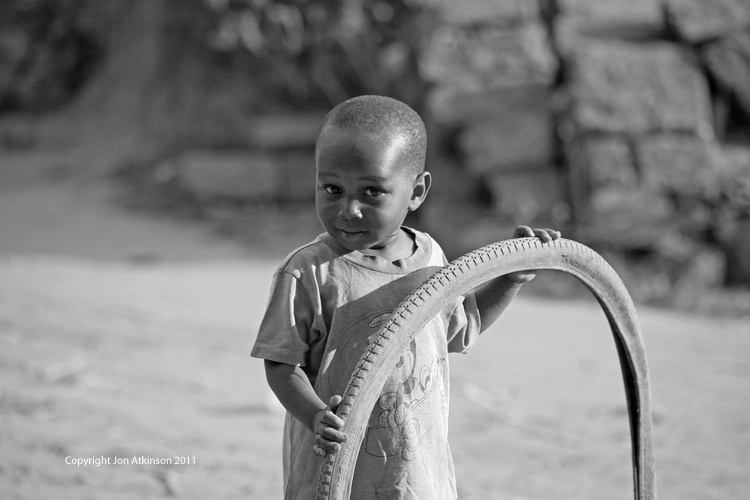 Child plays with bicycle tyre, Kenya